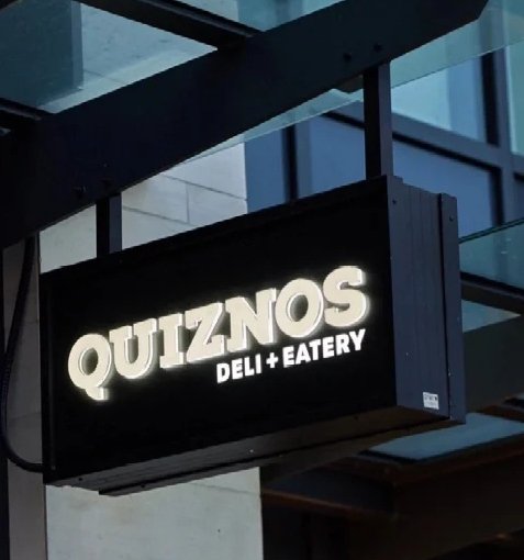 Illuminated double-sided blade sign cabinet for a commercial storefront