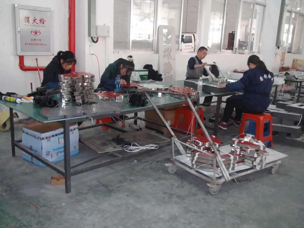 Production team assembling illuminated custom sign letters at worktables