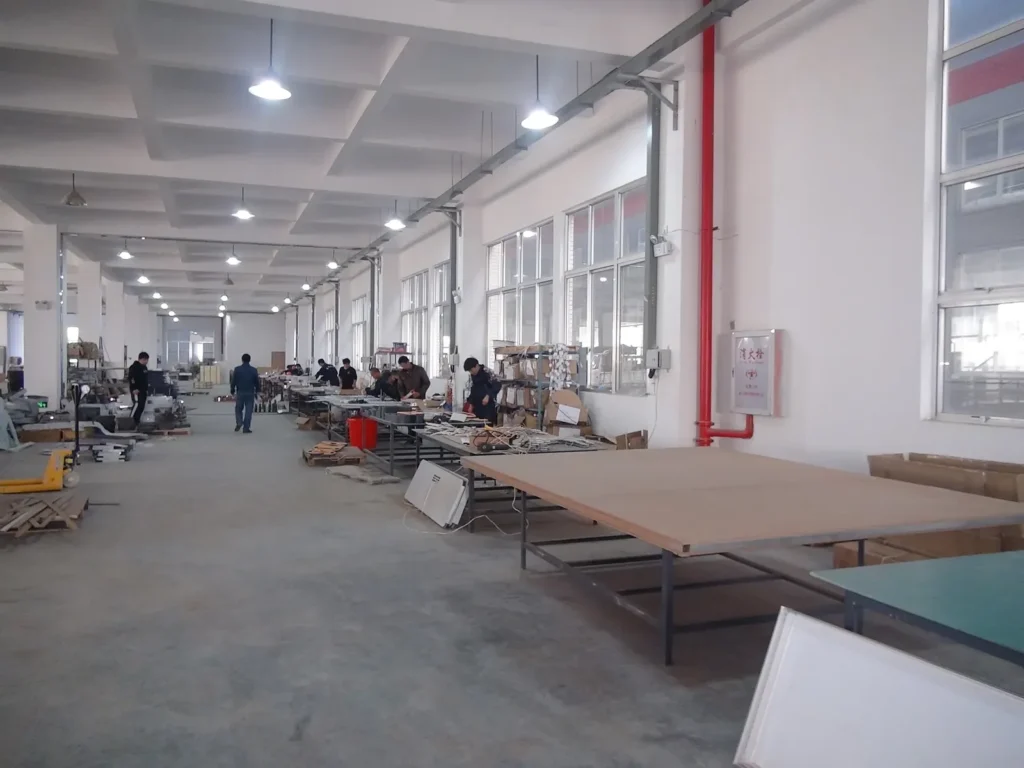 Wide custom sign assembly workshop with production tables and staff
